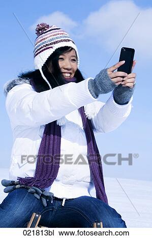 young asian woman in winter taking picture of herself with camera phone View Large Photo Image Stock Image - young asian woman in winter taking picture of herself with camera phone. Fotosearch