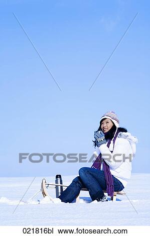 young asian woman sitting on sledge having drink from thermos bottle View Large Photo Image Stock Image - young asian woman sitting on sledge having drink from thermos bottle. Fotosearch