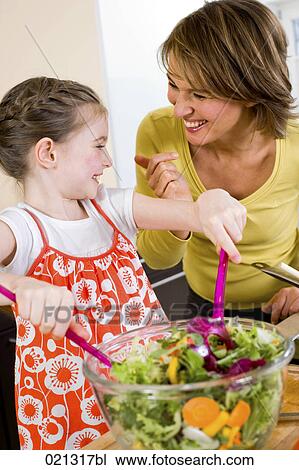 Stock Image - young girl and mother making salad. Fotosearch