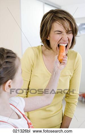 Stock Image - young girl feeding her mother carrot. Fotosearch