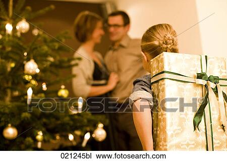 young girl hiding christmas present for parents behind her back View Large Photo Image Stock Image - young girl hiding christmas present for parents behind her back. Fotosearch