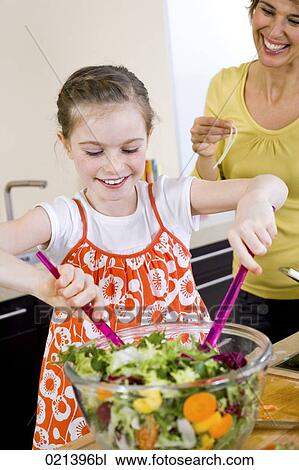 Stock Image - young girl inkitchen making salad. Fotosearch