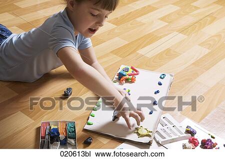 young girl lying on floor playing with modelling clay View Large Photo Image Stock Image - young girl lying on floor playing with modelling clay. Fotosearch