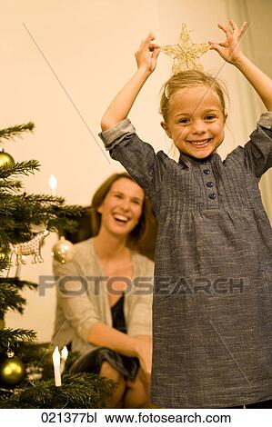 Stock Image - young girl making fun with star from christmas decoration. Fotosearch