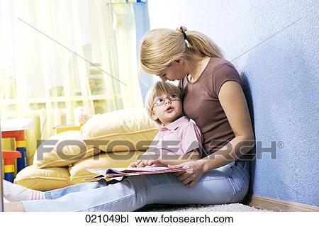 Stock Image - young mother reading from book to her son. Fotosearch