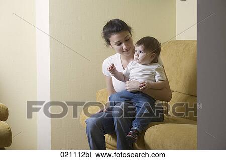 Stock Image - young mother sitting with her son on sofa. Fotosearch