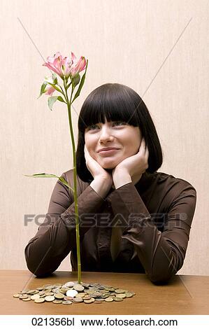 young woman looking at flower growing out of pile of coins View Large Photo Image Stock Image - young woman looking at flower growing out of pile of coins. Fotosearch