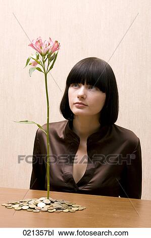 young woman looking at flower growing out of pile of coins View Large Photo Image Stock Image - young woman looking at flower growing out of pile of coins. Fotosearch