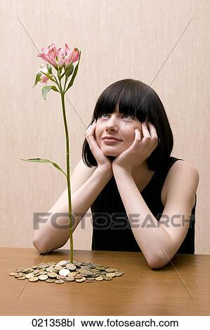 young woman looking at flower growing out of pile of coins View Large Photo Image Stock Image - young woman looking at flower growing out of pile of coins. Fotosearch