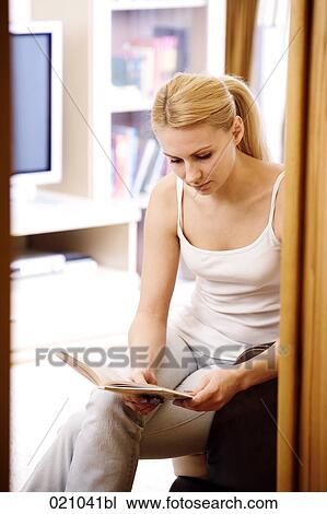 young woman sitting in living room reading book View Large Photo Image Stock Image - young woman sitting in living room reading book. Fotosearch