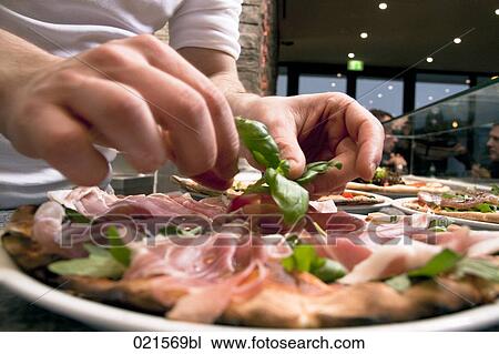 Stock Image - close-up of chef arranging bacon pizza. Fotosearch