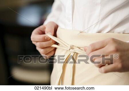Stock Image - close-up of waitress in restaurant tying apron. Fotosearch