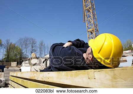 Stock Image - construction worker taking a nap on construction site. Fotosearch