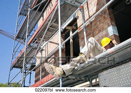Stock Image - construction worker taking a nap on scaffolding. Fotosearch