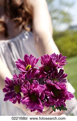 Stock Image - detail of youg woman holding bunch of purple flowers. Fotosearch