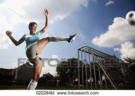 Stock Image - female football player kicking ball. Fotosearch