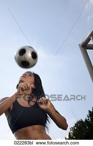 Stock Image - female football player practising header. Fotosearch