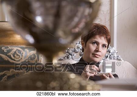 mature woman sitting in living room drinking coffee View Large Photo Image Stock Image - mature woman sitting in living room drinking coffee. Fotosearch