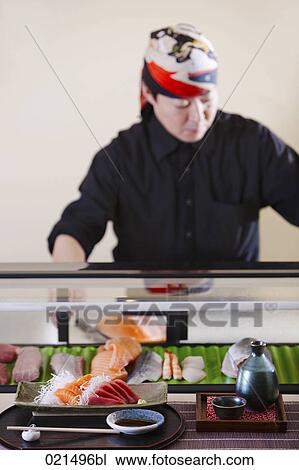 Stock Image - portrait of japanese chef in presenting sushi in restaurant. Fotosearch
