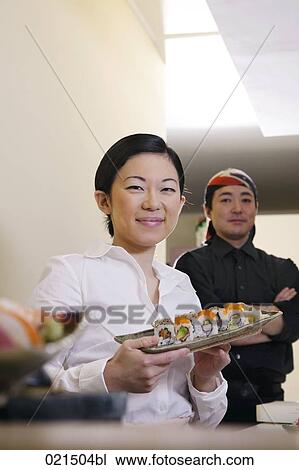 Stock Image - portrait of japanese waitress and chef with sushi. Fotosearch