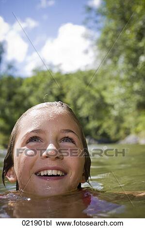 Stock Image - portrait of young girl swimming in water. Fotosearch