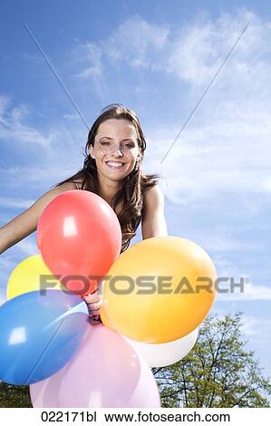 portrait of young woman holding colourful balloons View Large Photo Image Stock Image - portrait of young woman holding colourful balloons. Fotosearch