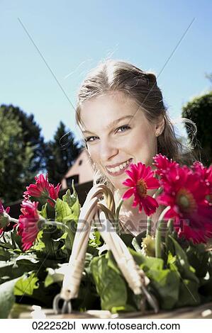 Stock Image - portrait of young woman with basket full of flowers. Fotosearch