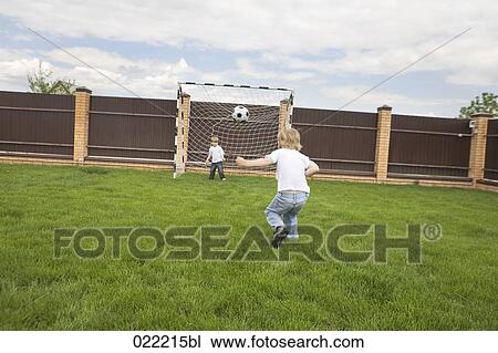 rear view of young boy kicking football into goal View Large Photo Image Stock Image - rear view of young boy kicking football into goal. Fotosearch