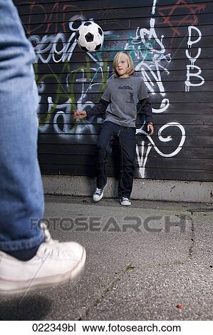 Stock Image - two young boys playing street football. Fotosearch