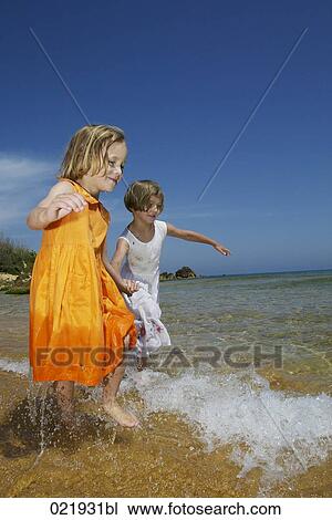 two young sisters running through surf on beach View Large Photo Image Stock Image - two young sisters running through surf on beach. Fotosearch