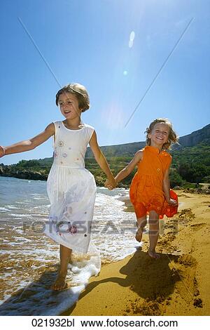 two young sisters running through surf on beach View Large Photo Image Stock Image - two young sisters running through surf on beach. Fotosearch