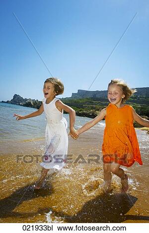 two young sisters running through surf on beach View Large Photo Image Stock Image - two young sisters running through surf on beach. Fotosearch