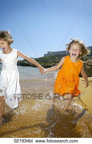 two young sisters running through surf on beach View Large Photo Image Stock Image - two young sisters running through surf on beach. Fotosearch