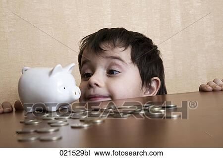 young boy behind table looking at piggybank View Large Photo Image Stock Image - young boy behind table looking at piggybank. Fotosearch