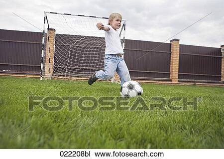 Stock Image - young boy kicking football. Fotosearch
