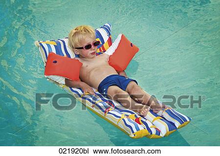 young boy lying on air bed floating in swimming pool View Large Photo Image Stock Image - young boy lying on air bed floating in swimming pool. Fotosearch