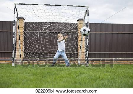 young boy standing in football goal catching ball View Large Photo Image Stock Image - young boy standing in football goal catching ball. Fotosearch