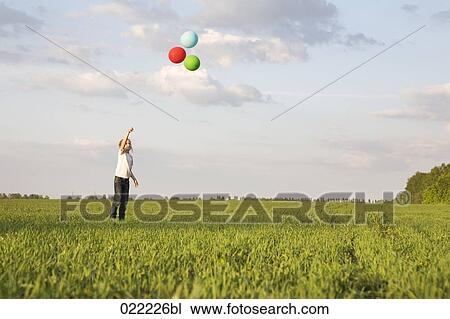young girl standing in field letting ballons fly View Large Photo Image Stock Image - young girl standing in field letting ballons fly. Fotosearch
