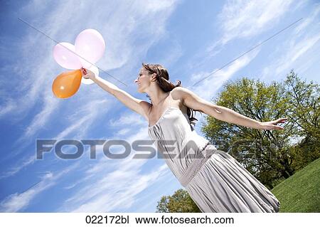 young woman in park letting balloons fly View Large Photo Image Stock Image - young woman in park letting balloons fly. Fotosearch