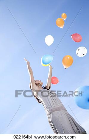 young woman letting balloons fly up in the sky View Large Photo Image Stock Image - young woman letting balloons fly up in the sky. Fotosearch