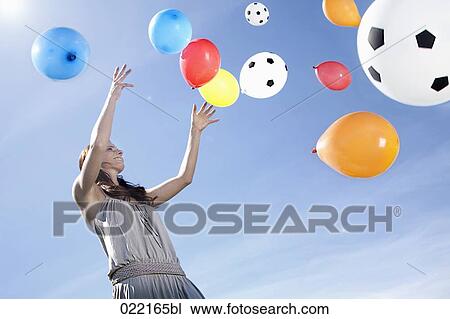 young woman letting balloons fly up in the sky View Large Photo Image Stock Image - young woman letting balloons fly up in the sky. Fotosearch