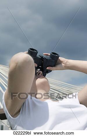 young woman lying in hammock watching the sky with binoculars View Large Photo Image Stock Image - young woman lying in hammock watching the sky with binoculars. Fotosearch