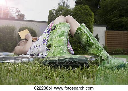 young woman lying on grass in garden reading books View Large Photo Image Stock Image - young woman lying on grass in garden reading books. Fotosearch