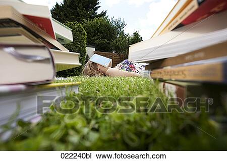 young woman lying on grass in garden reading books View Large Photo Image Stock Image - young woman lying on grass in garden reading books. Fotosearch