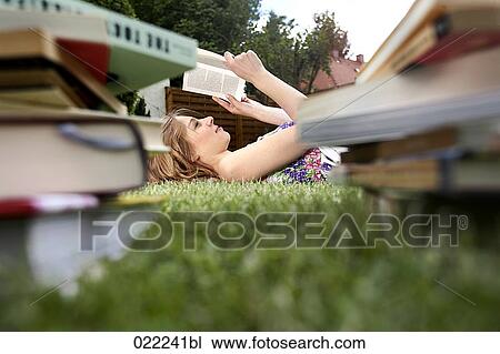 young woman lying on grass in garden reading books View Large Photo Image Stock Image - young woman lying on grass in garden reading books. Fotosearch