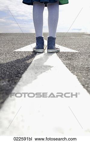 detail of young girl standing on arrow sign on road View Large Photo Image Stock Image - detail of young girl standing on arrow sign on road. Fotosearch
