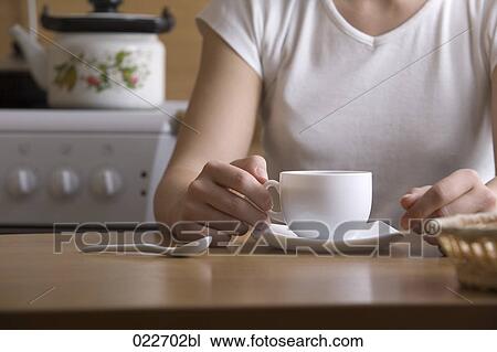 detail of young woman sitting at table with cup View Large Photo Image Stock Image - detail of young woman sitting at table with cup. Fotosearch