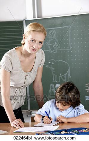 female teacher helping young pupil at school View Large Photo Image Stock Image - female teacher helping young pupil at school. Fotosearch