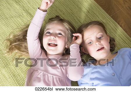 portrait of two young girls lying on floor View Large Photo Image Stock Image - portrait of two young girls lying on floor. Fotosearch