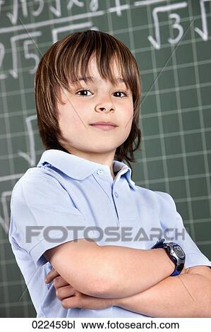 Stock Image - portrait of young boy in classroom in front pof blackboard. Fotosearch